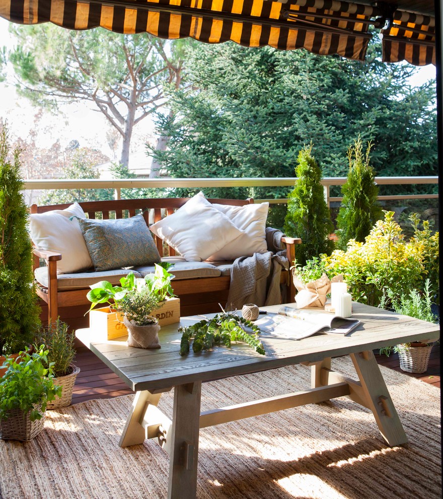 Immagine di una piccola terrazza shabby-chic style con un giardino in vaso e un parasole