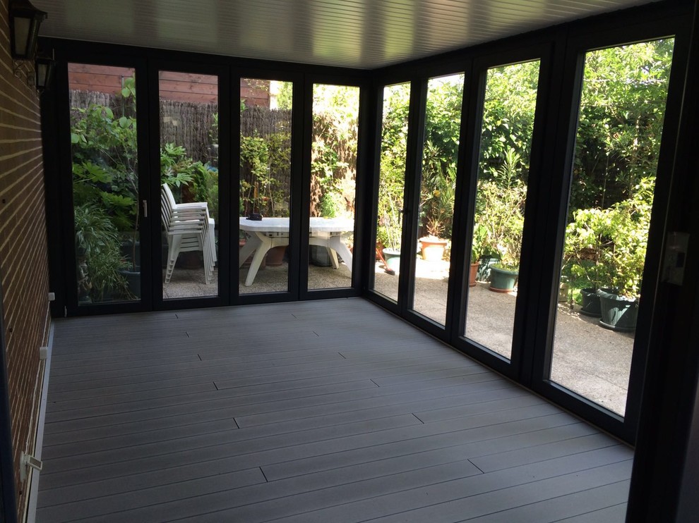Mid-sized transitional backyard deck photo in Madrid with a roof extension