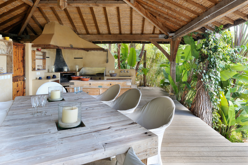 Modelo de terraza tropical grande en patio trasero con brasero, entablado y pérgola