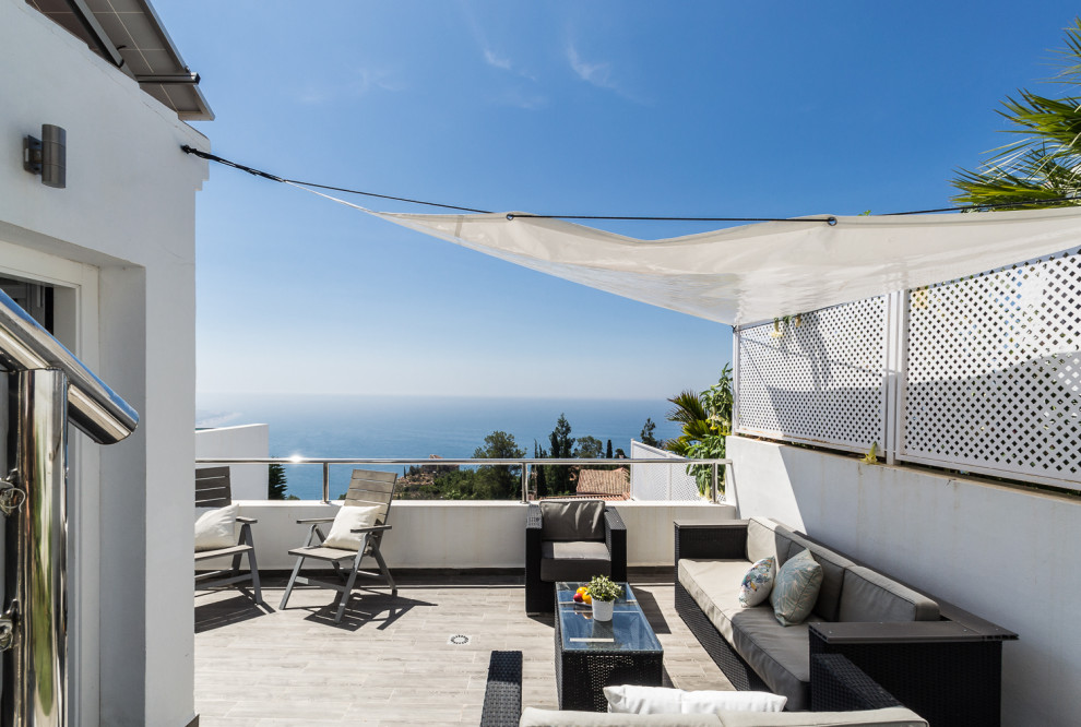 Diseño de terraza mediterránea de tamaño medio en patio lateral con ducha exterior y toldo
