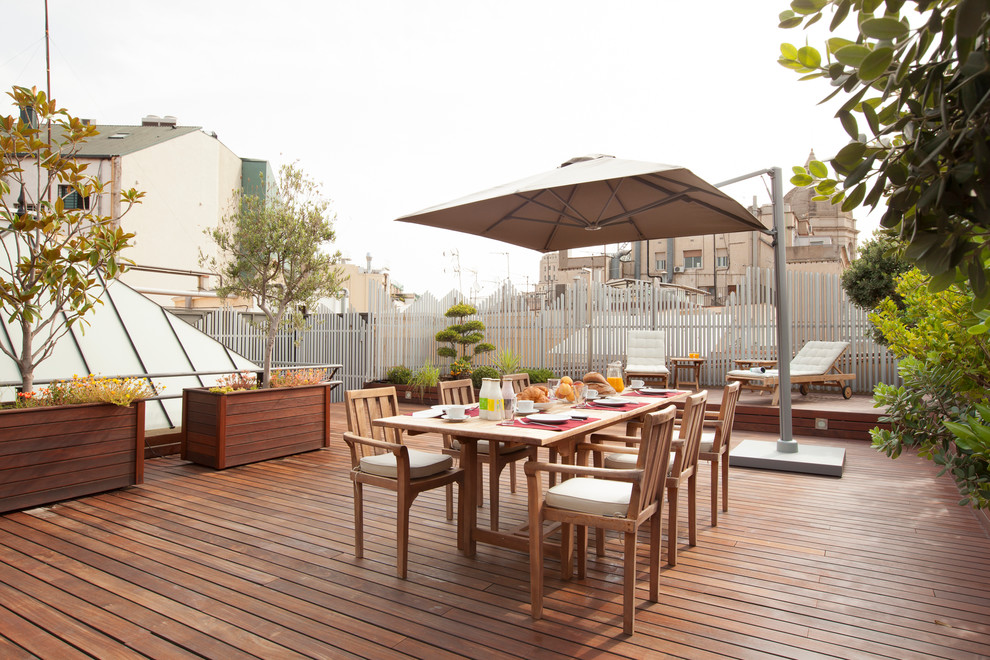 This is an example of a large contemporary roof terrace in Barcelona with a potted garden and an awning.