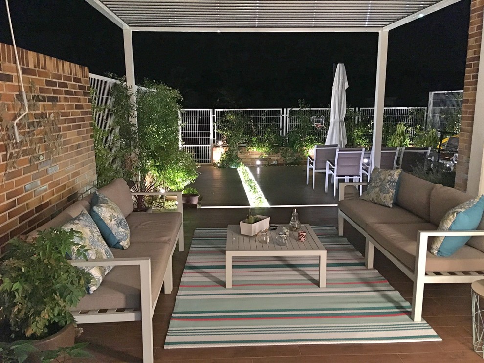 Ejemplo de terraza contemporánea de tamaño medio en patio trasero con jardín vertical, suelo de baldosas y pérgola