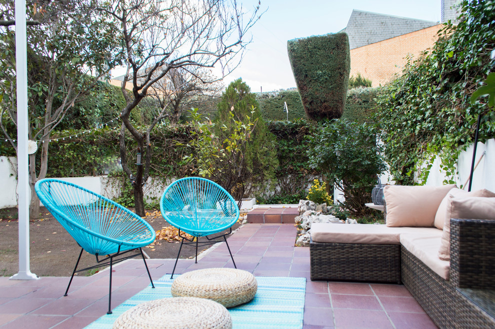 Modelo de terraza minimalista de tamaño medio en patio trasero con jardín de macetas, suelo de baldosas y toldo