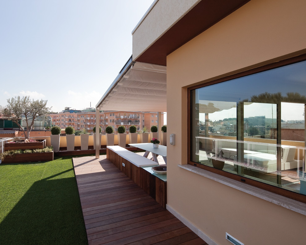 This is an example of an expansive modern roof terrace in Rome with a potted garden and an awning.