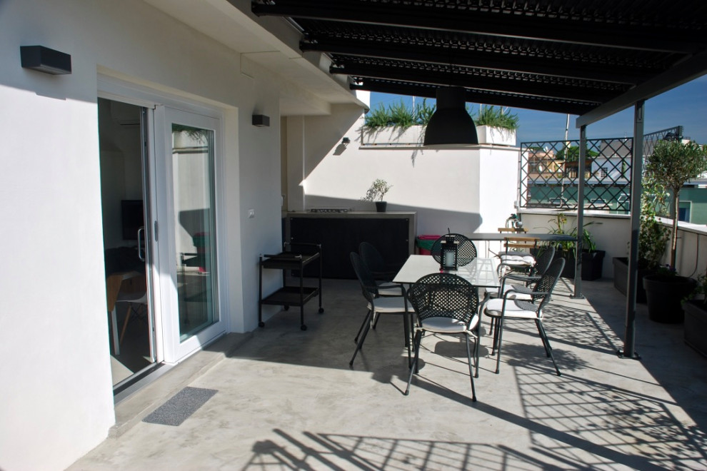 This is an example of an expansive scandi roof terrace in Rome with an outdoor kitchen and an awning.
