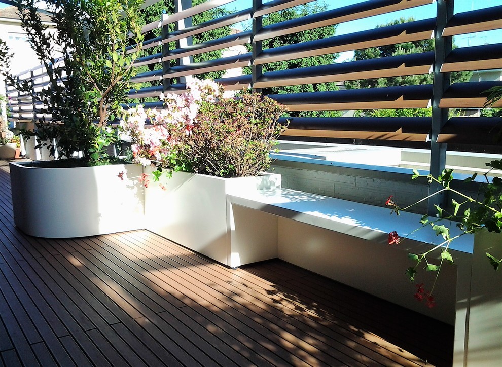 This is an example of an expansive contemporary roof terrace in Milan with a potted garden and an awning.