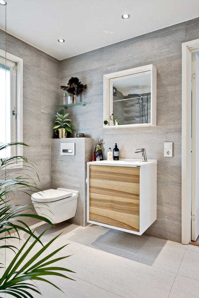 Bild på ett mellanstort tropiskt toalett, med en vägghängd toalettstol, vita väggar, mellanmörkt trägolv och ett väggmonterat handfat