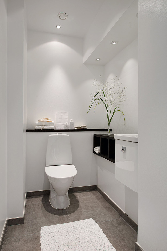 На фото: туалет среднего размера в скандинавском стиле с плоскими фасадами, белыми фасадами, раздельным унитазом и серым полом