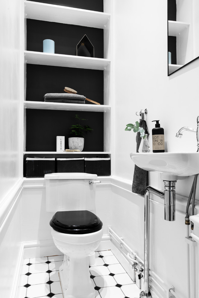 Modelo de aseo clásico renovado pequeño con armarios abiertos, sanitario de una pieza, lavabo suspendido, suelo multicolor y paredes negras
