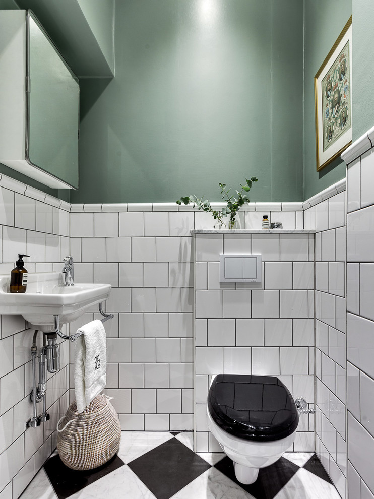 Inredning av ett klassiskt toalett, med en vägghängd toalettstol, keramikplattor, gröna väggar, ett väggmonterat handfat och flerfärgat golv