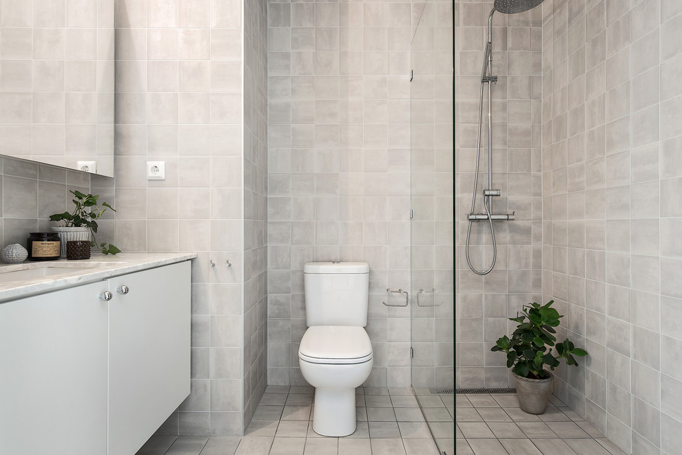 На фото: туалет среднего размера в скандинавском стиле с унитазом-моноблоком, бежевой плиткой, керамогранитной плиткой и накладной раковиной с