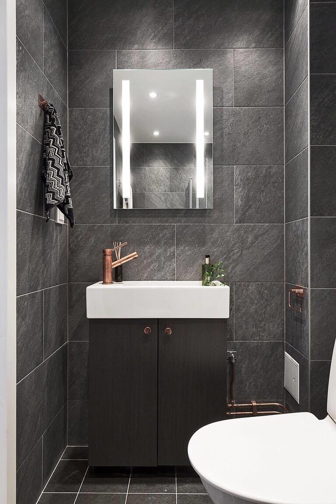 Small contemporary cloakroom in Stockholm with flat-panel cabinets, black cabinets, black walls, ceramic flooring, a two-piece toilet, an integrated sink, grey tiles, grey floors and slate tiles.