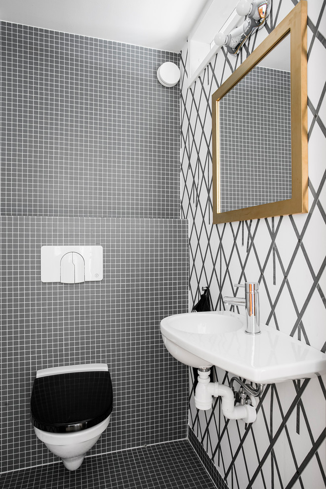 Idéer för att renovera ett litet funkis vit vitt toalett, med en vägghängd toalettstol, ett väggmonterat handfat, svart kakel, vita väggar och svart golv