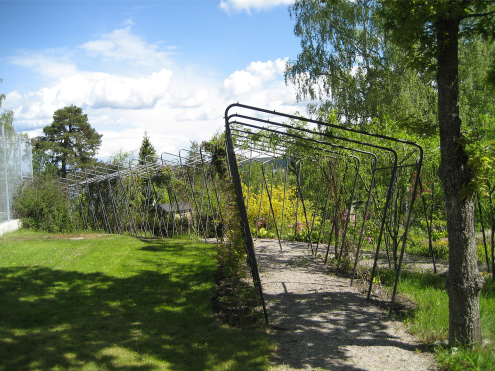 Foto på en stor funkis bakgård i delvis sol, med en trädgårdsgång och grus