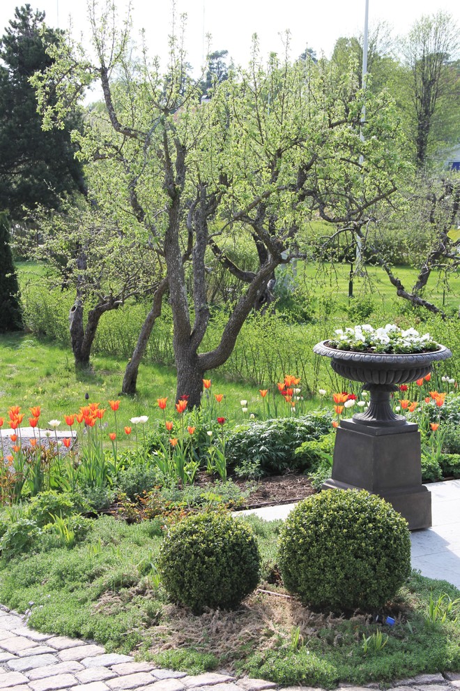 Modelo de jardín clásico de tamaño medio en primavera en patio trasero con jardín francés, exposición total al sol y adoquines de piedra natural