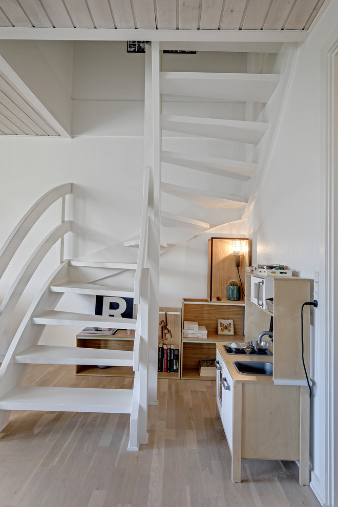 Стильный дизайн: изогнутая лестница в скандинавском стиле с крашенными деревянными ступенями, крашенными деревянными подступенками и деревянными перилами - последний тренд