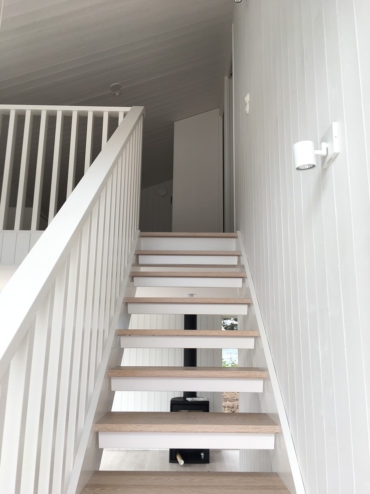 Ejemplo de escalera recta nórdica con escalones de madera, contrahuellas de madera y barandilla de madera
