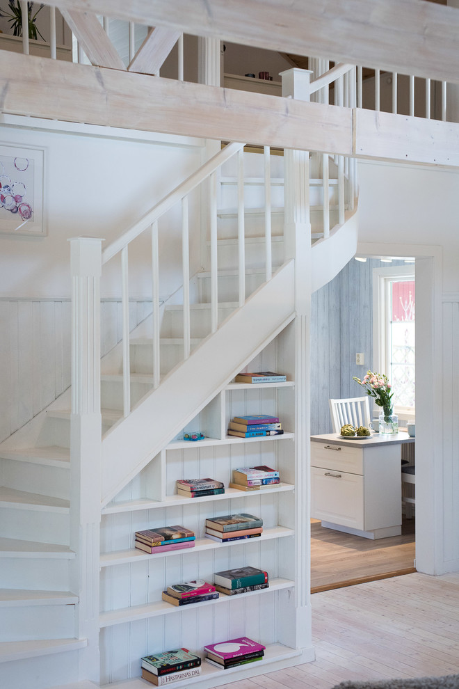 Design ideas for a country painted wood curved wood railing staircase in Stockholm with painted wood risers and under stair storage.