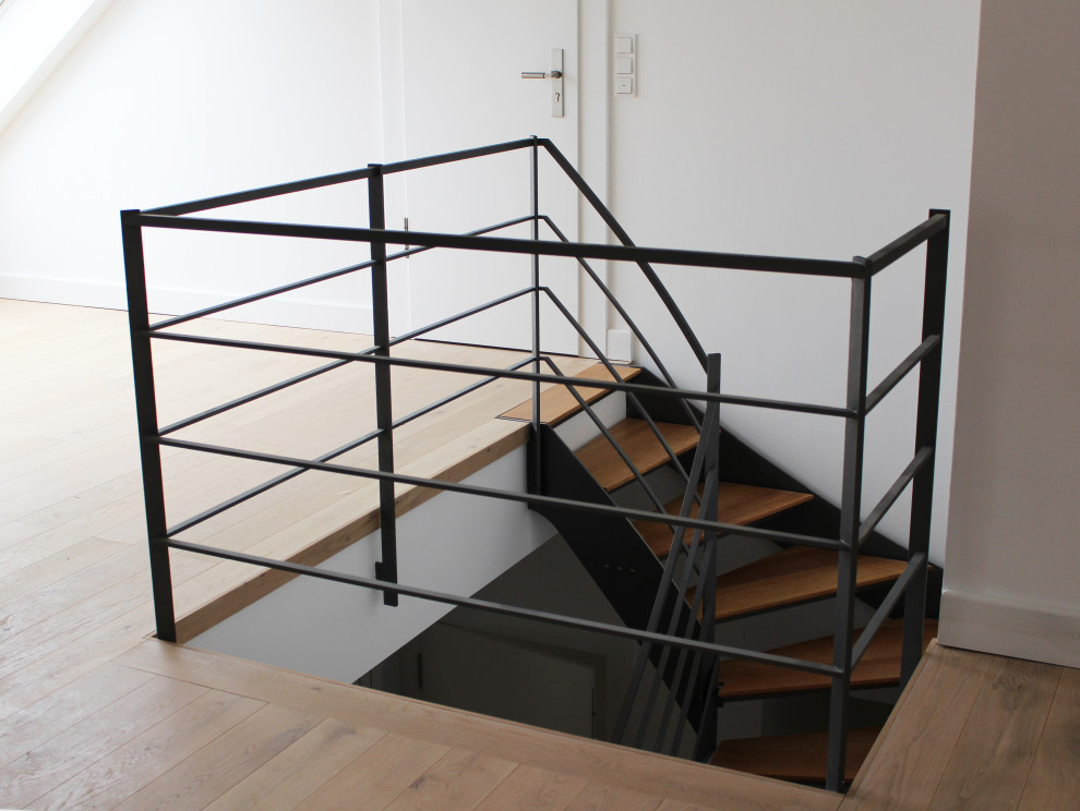 Aménagement d'un très grand escalier courbe contemporain avec des marches en bois et un garde-corps en métal.