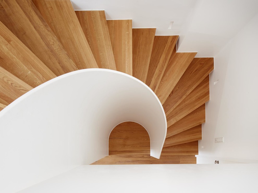 Réalisation d'un escalier courbe design avec des marches en bois et des contremarches en bois.