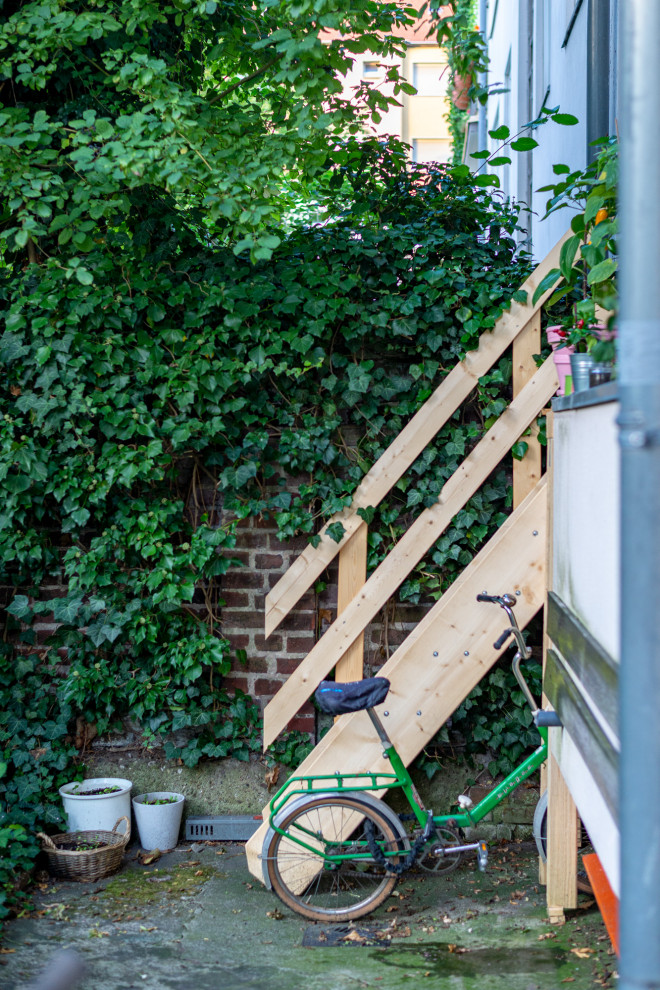 На фото: маленькая прямая деревянная лестница в стиле кантри с деревянными ступенями и деревянными перилами для на участке и в саду