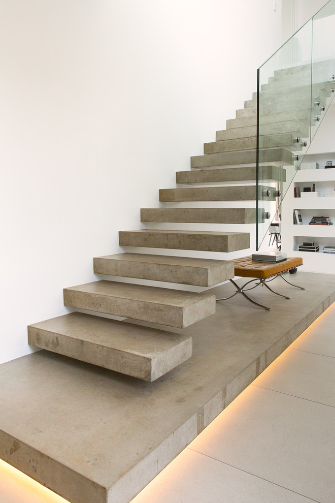 Photo of a medium sized modern concrete straight glass railing staircase in Hamburg with open risers and feature lighting.