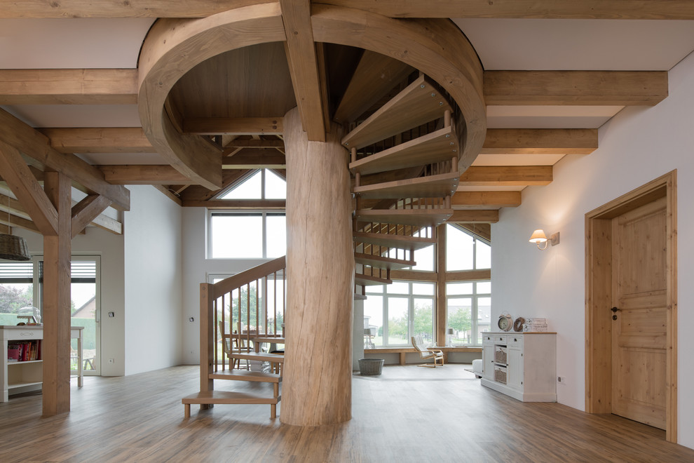 На фото: большая винтовая лестница в стиле рустика с деревянными ступенями без подступенок с
