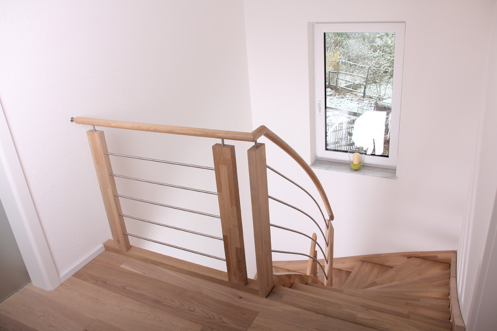 Ejemplo de escalera curva contemporánea de tamaño medio con escalones de madera y barandilla de madera