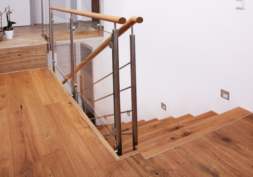 Ispirazione per una scala a rampa dritta contemporanea di medie dimensioni con pedata in legno, alzata in legno e parapetto in vetro