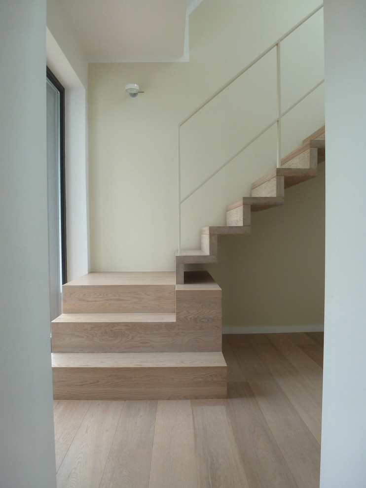 Imagen de escalera contemporánea con escalones de madera pintada, contrahuellas de madera pintada y barandilla de metal