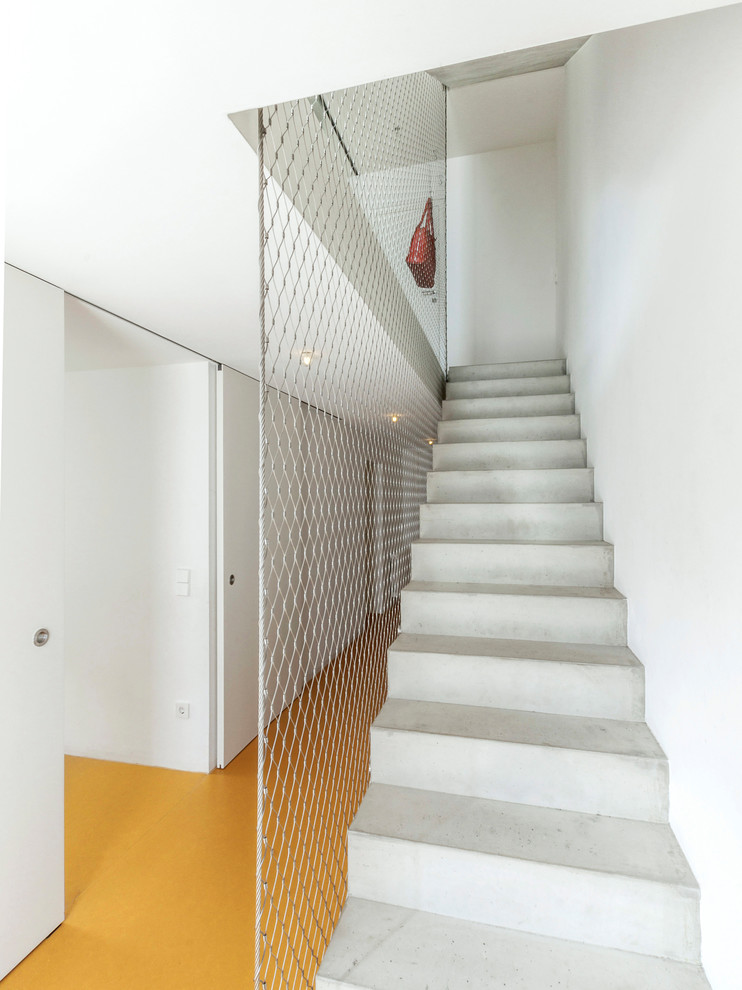 Imagen de escalera recta urbana de tamaño medio con escalones de hormigón, contrahuellas de hormigón y barandilla de metal