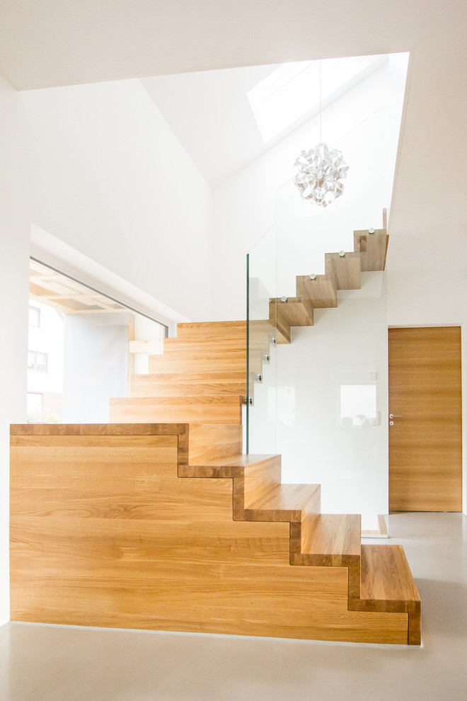 Пример оригинального дизайна: лестница в современном стиле с стеклянными перилами