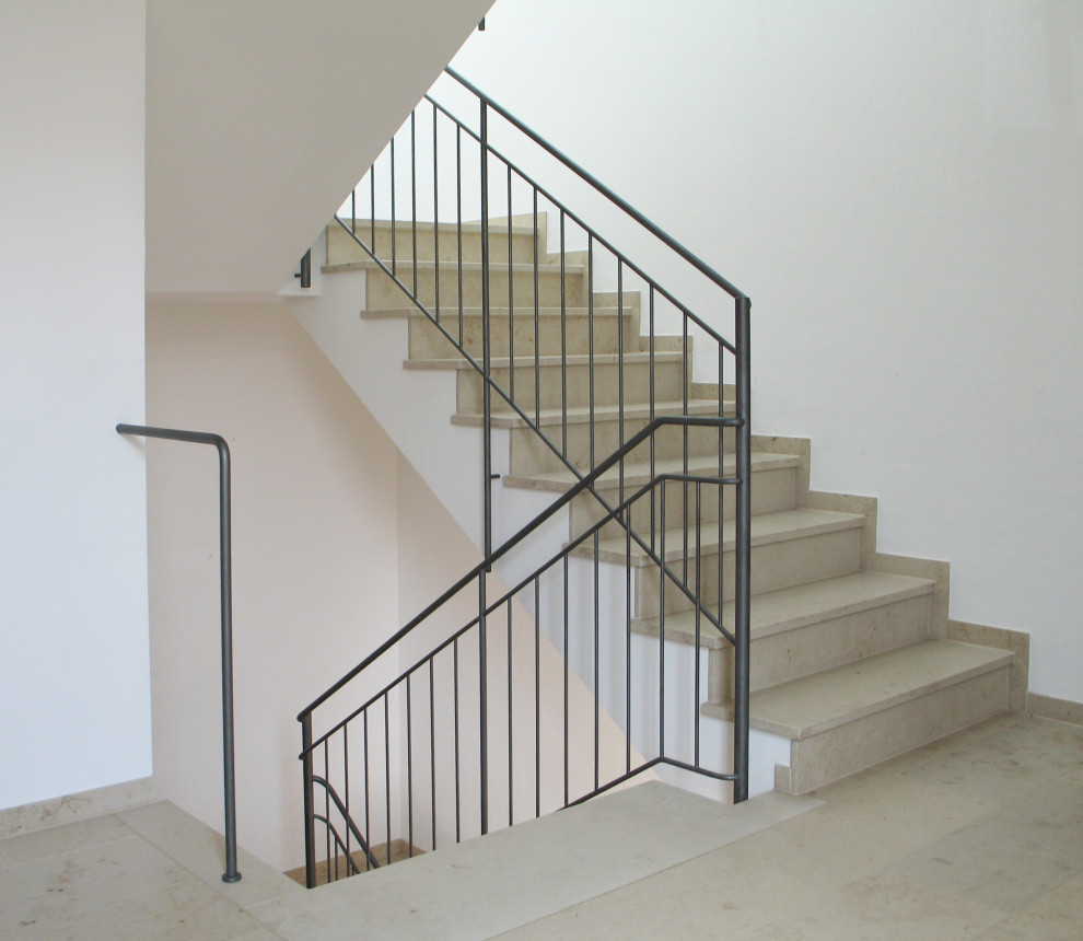 Example of a large trendy marble straight metal railing staircase design in Dusseldorf with marble risers