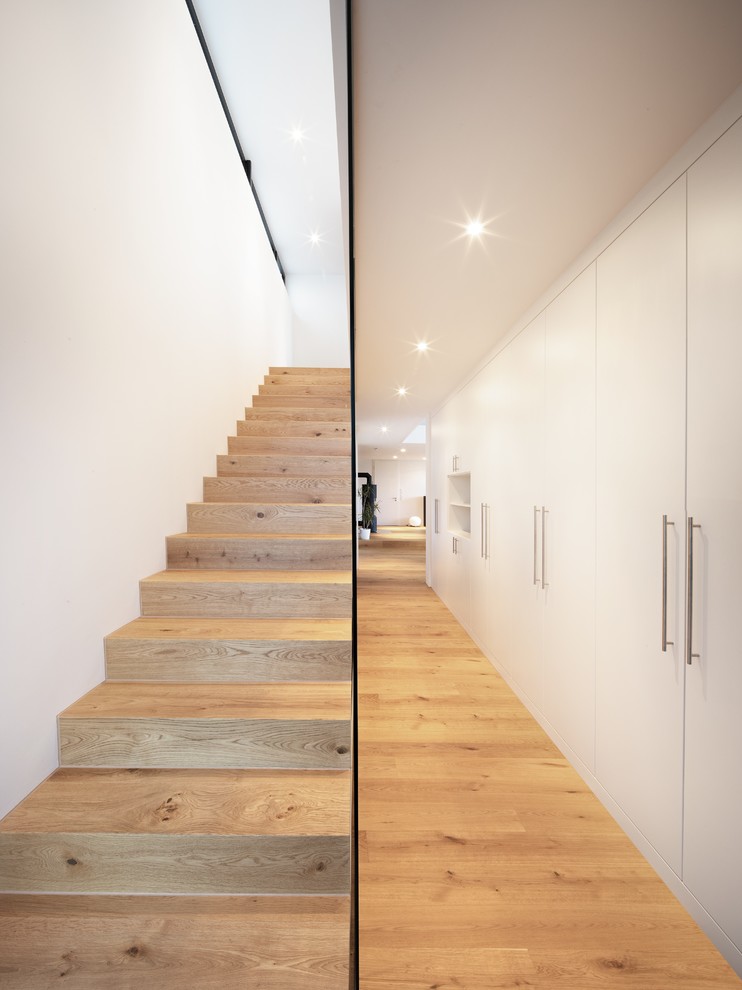Foto de escalera recta moderna de tamaño medio con escalones de madera pintada, contrahuellas de madera pintada y barandilla de vidrio