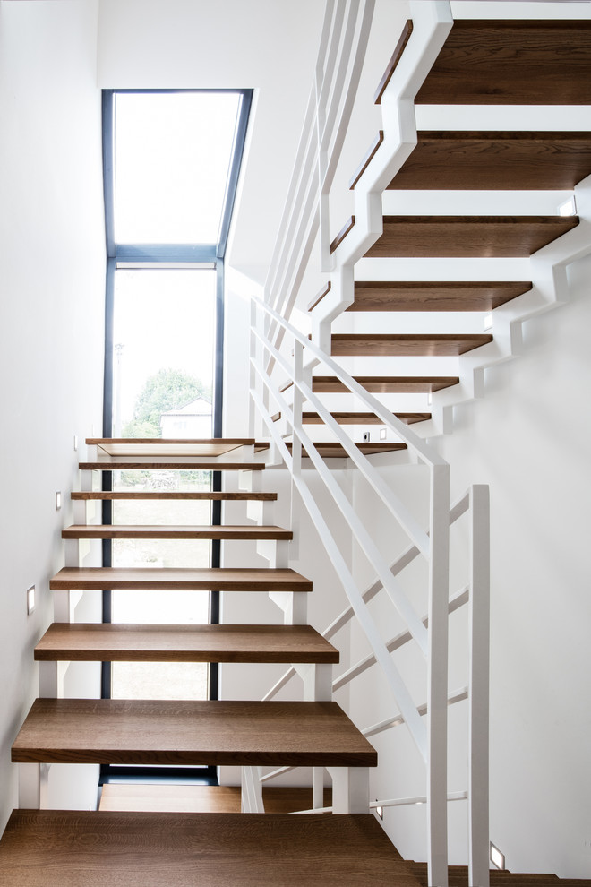 Medium sized contemporary wood u-shaped staircase in Stuttgart with open risers.