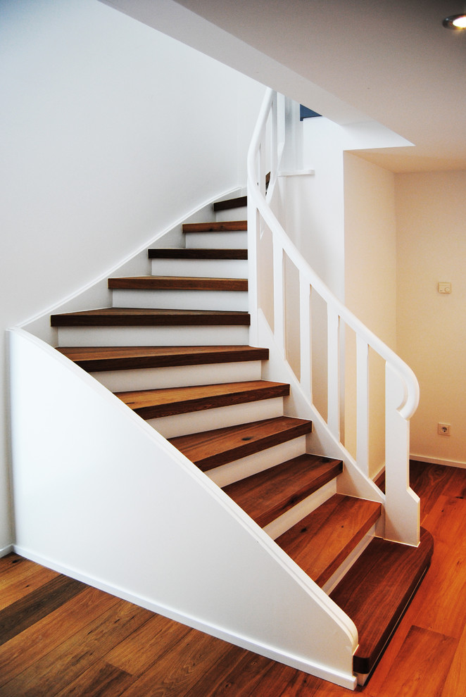 Свежая идея для дизайна: изогнутая лестница среднего размера в современном стиле с деревянными ступенями - отличное фото интерьера