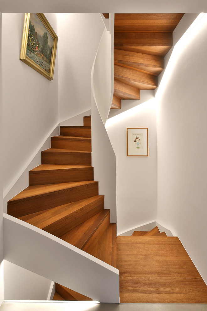 Imagen de escalera curva actual pequeña con escalones de madera, contrahuellas de madera y barandilla de madera
