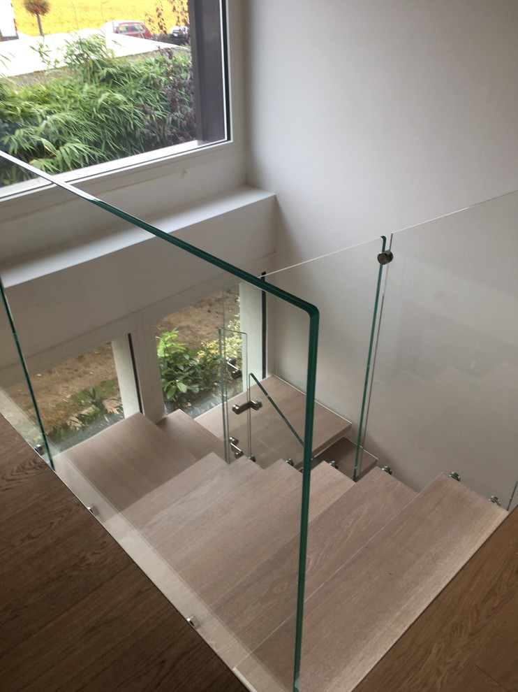 Exemple d'un escalier tendance en U de taille moyenne avec des marches en bois et un garde-corps en verre.