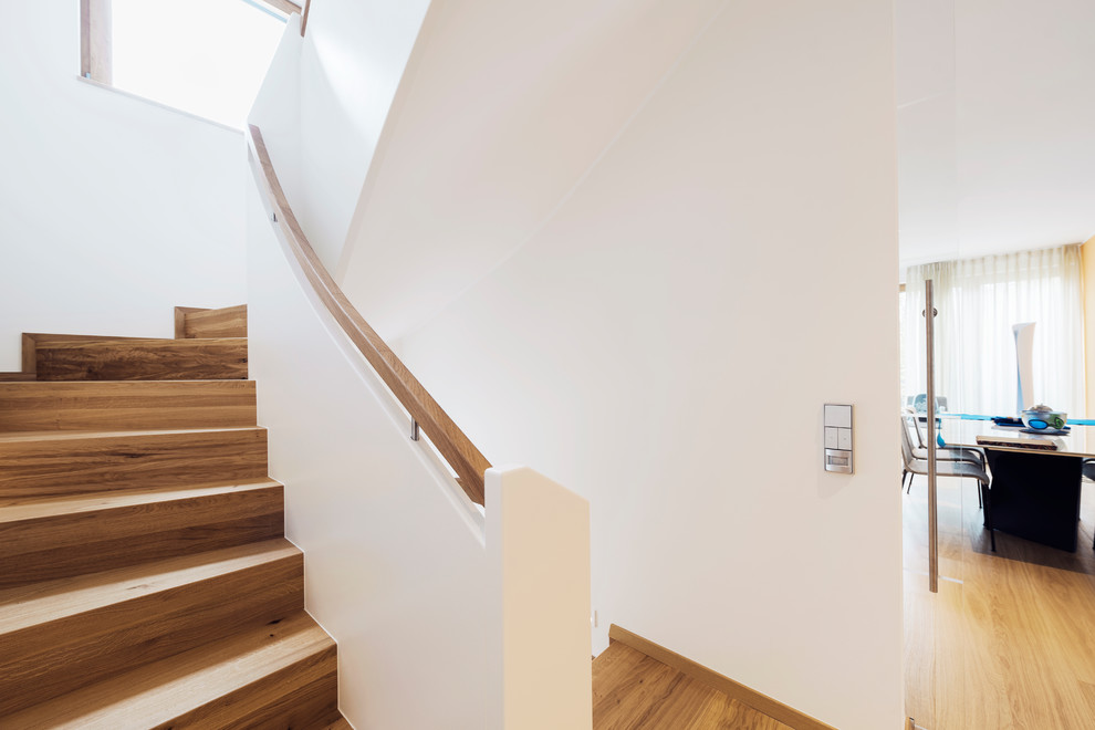Réalisation d'un escalier courbe design de taille moyenne avec des marches en bois, des contremarches en bois et un garde-corps en matériaux mixtes.