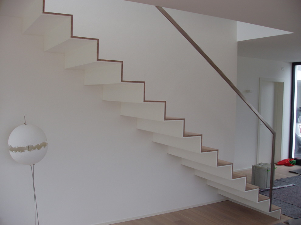 Imagen de escalera recta minimalista grande con escalones de madera pintada, contrahuellas de madera pintada y barandilla de metal