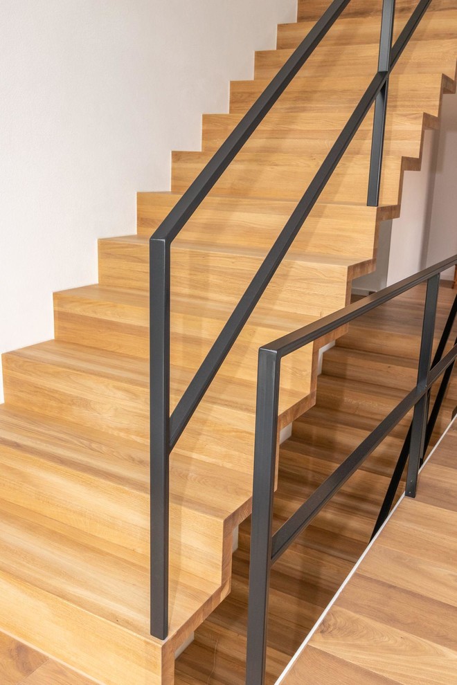 Idées déco pour un escalier moderne avec des marches en bois, des contremarches en bois et un garde-corps en métal.
