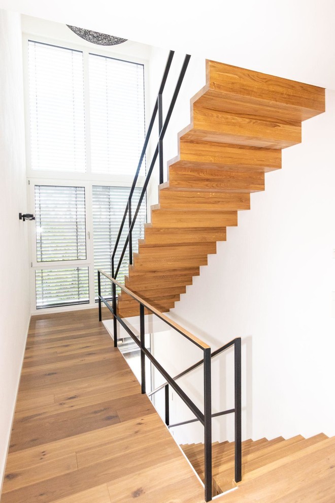 Exemple d'un escalier moderne avec des marches en bois, des contremarches en bois et un garde-corps en métal.
