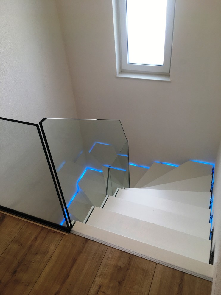 Inspiration pour un grand escalier courbe design avec des marches en bois, des contremarches en bois et un garde-corps en verre.