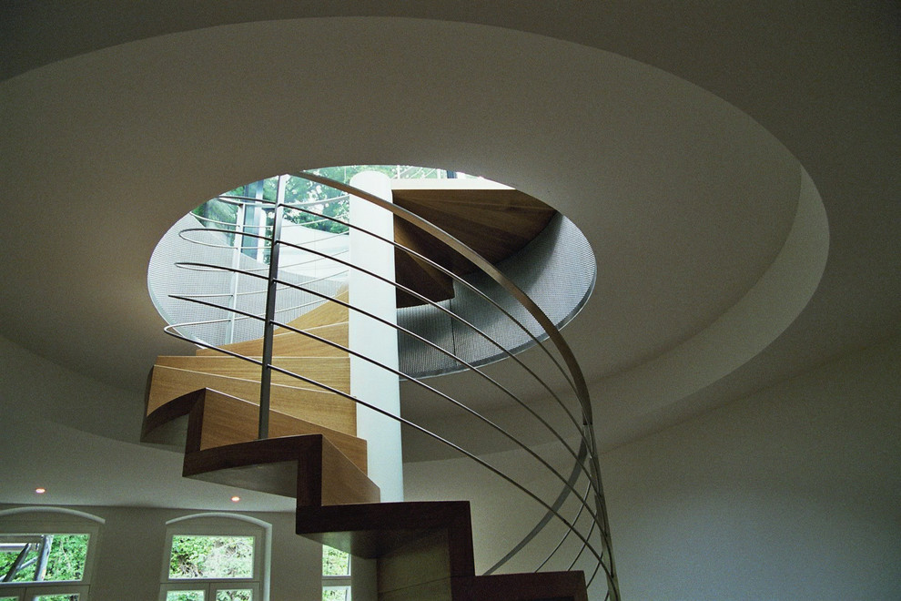Imagen de escalera actual extra grande con escalones de madera, contrahuellas de madera y barandilla de metal