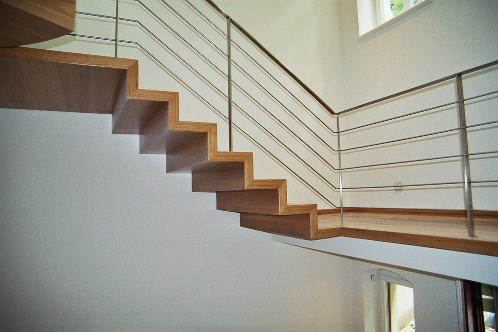 Cette image montre un très grand escalier design avec des marches en bois, des contremarches en bois et un garde-corps en métal.