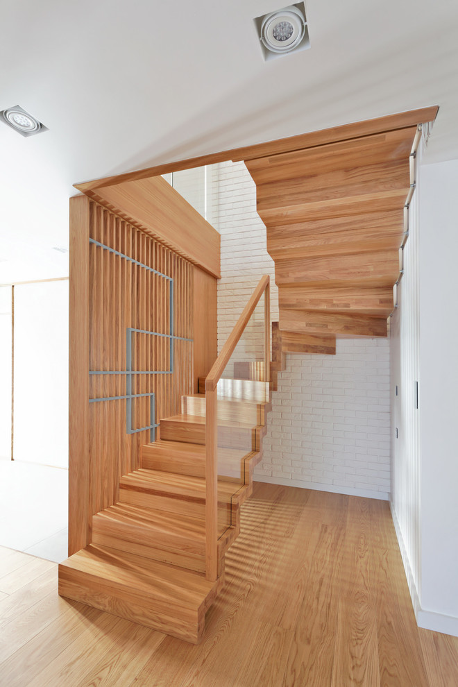 Aménagement d'un escalier contemporain en U de taille moyenne avec un garde-corps en matériaux mixtes, des marches en bois, des contremarches en bois et éclairage.