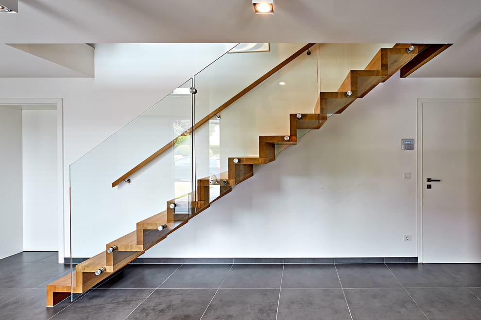 他の地域にある高級な広いコンテンポラリースタイルのおしゃれな直階段 (木の蹴込み板、ガラスフェンス) の写真