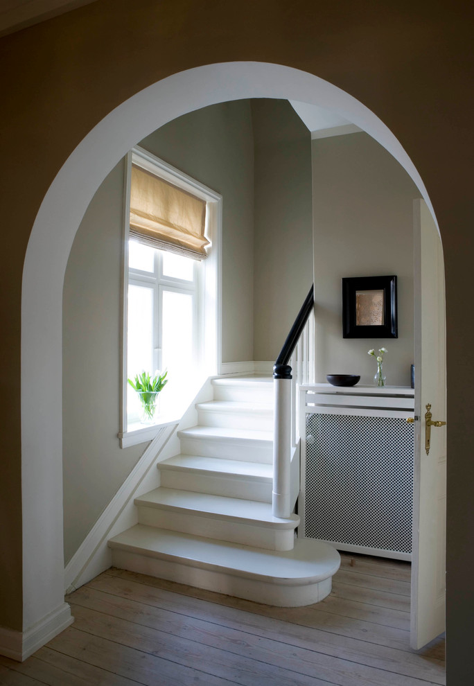 На фото: изогнутая деревянная лестница в стиле кантри с деревянными ступенями