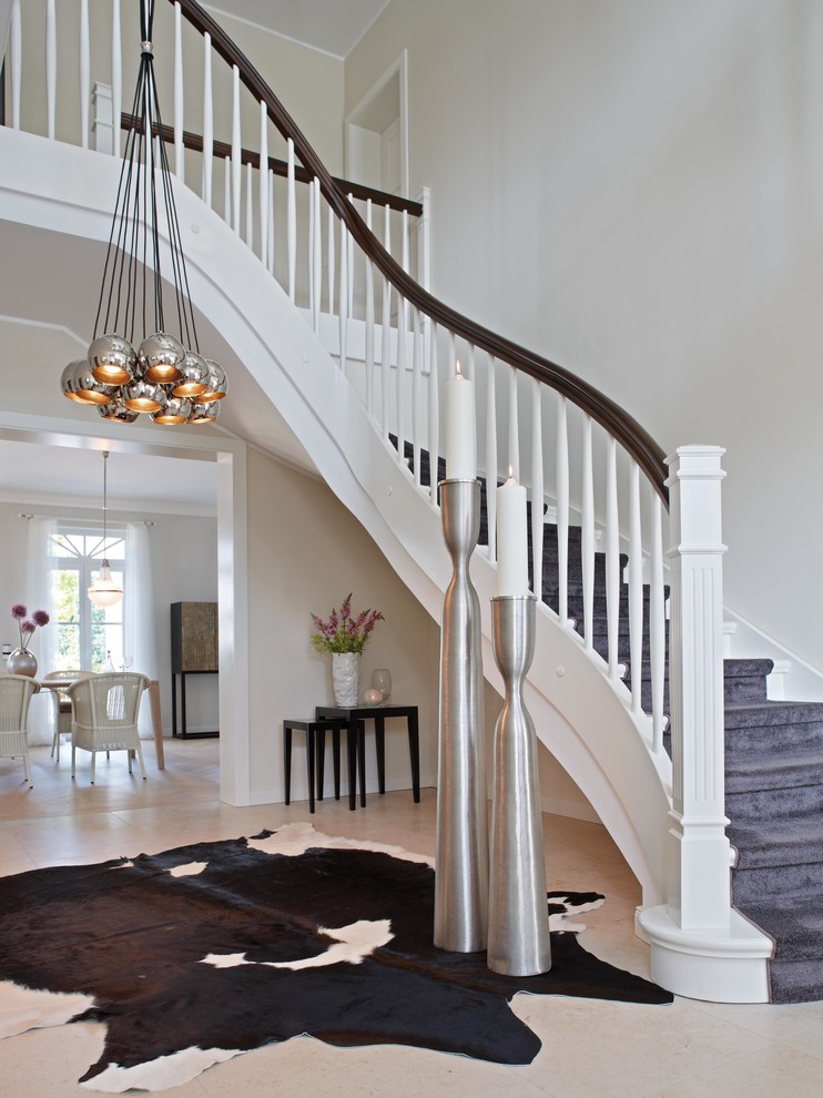 Пример оригинального дизайна: большая изогнутая лестница в стиле неоклассика (современная классика) с крашенными деревянными ступенями и крашенными деревянными подступенками