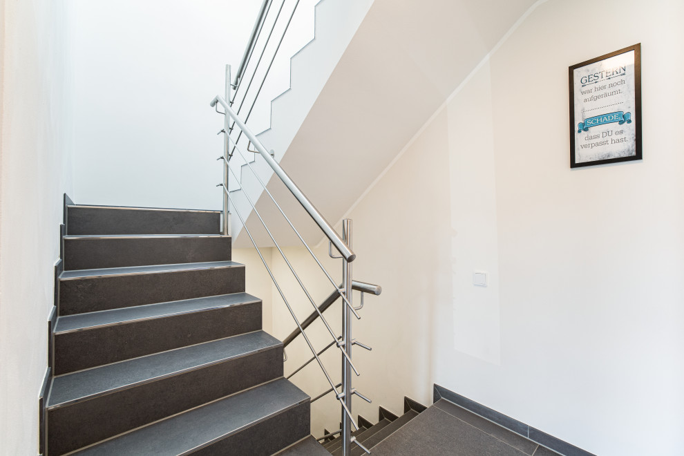 Mittelgroße Moderne Treppe in U-Form mit gefliesten Treppenstufen, gefliesten Setzstufen und Stahlgeländer in Düsseldorf